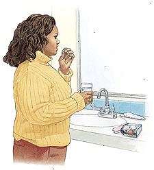 Mujer de pie en el lavabo del baño que toma la píldora anticonceptiva. Mujer de pie en el lavabo del baño que toma la píldora anticonceptiva.