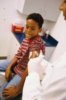 Foto de un muchacho joven que se prepara para recibir una inyección de vacunación de su médico