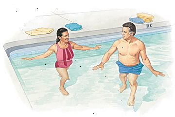 Hombre y mujer que camina en parte menos profunda de la piscina.