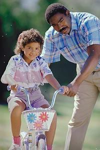 Imagen de un padre enseñando a su hija a andar en bicicleta Imagen de un padre enseñando a su hija a andar en bicicleta
