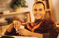 Fotografía de un hombre joven y sonriente, sosteniendo una taza de café Fotografía de un hombre joven y sonriente, sosteniendo una taza de café