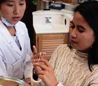 Imagen de una chica joven que es instruido por su dentista sobre la forma de usar el hilo dental Imagen de una chica joven que es instruido por su dentista sobre la forma de usar el hilo dental
