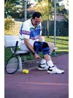 Fotografía de un hombre que llevaba una llave de rodilla, jugando al tenis Fotografía de un hombre que llevaba una llave de rodilla, jugando al tenis