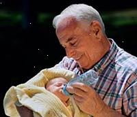 Fotografía de un abuelo cargando a su nieto recién nacido, la alimentación de él una botella Fotografía de un abuelo cargando a su nieto recién nacido, la alimentación de él una botella